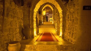 A stone-walled corridor with a red carpet leading to a staircase. A large pot is visible on the left, and the number 101 is on the right wall. - Euphoria Cave House (Nevsehir)