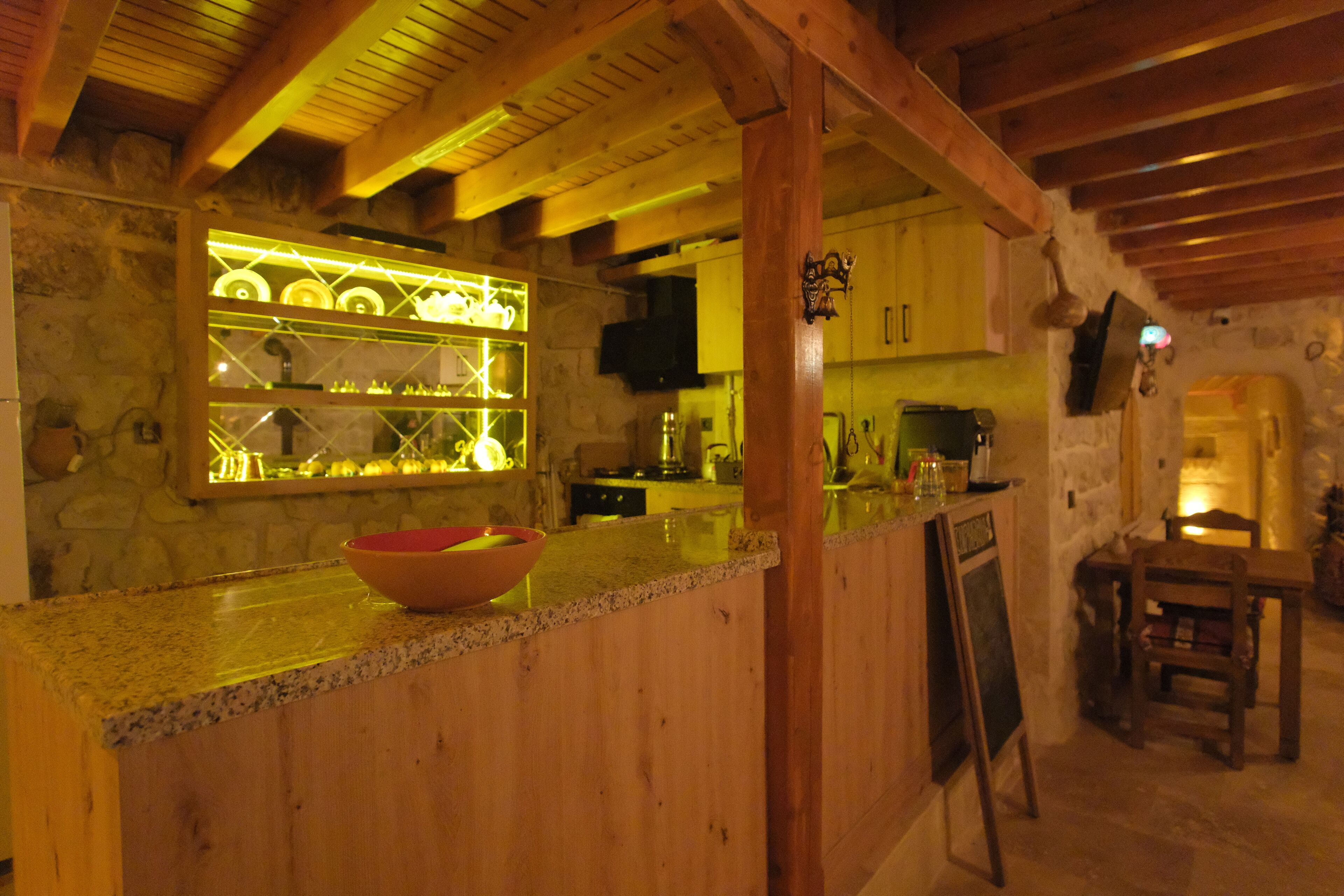 A rustic kitchen with wooden beams, a stone wall, and a bar area with a bowl on the counter.