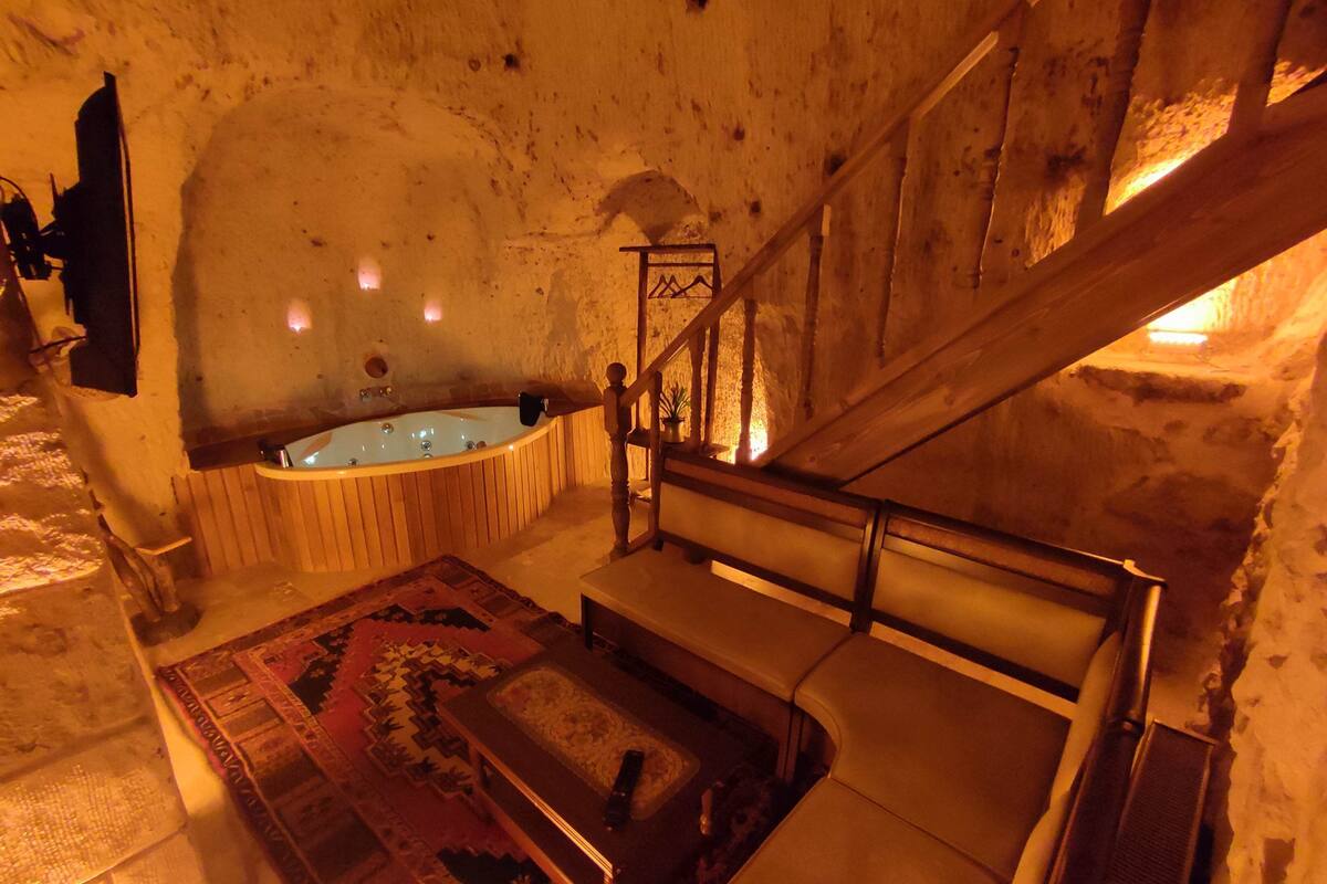 A room with a wooden staircase, a wooden bathtub, and a patterned rug.