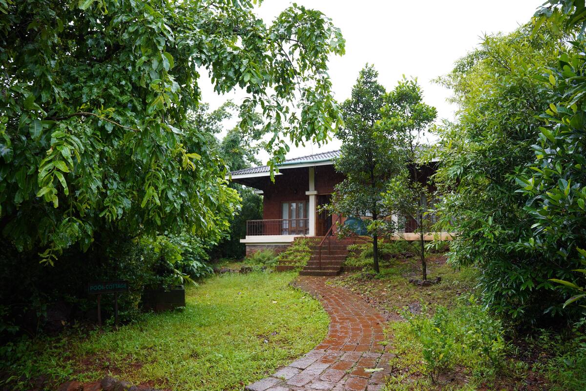 A brick pathway leading to a cottage with a sloped roof and a small porch.