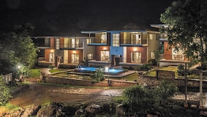 A modern two-story house with a swimming pool, a well-maintained garden, and a stone pathway leading to the entrance. - Forest Escapes Koyna (Patan)
