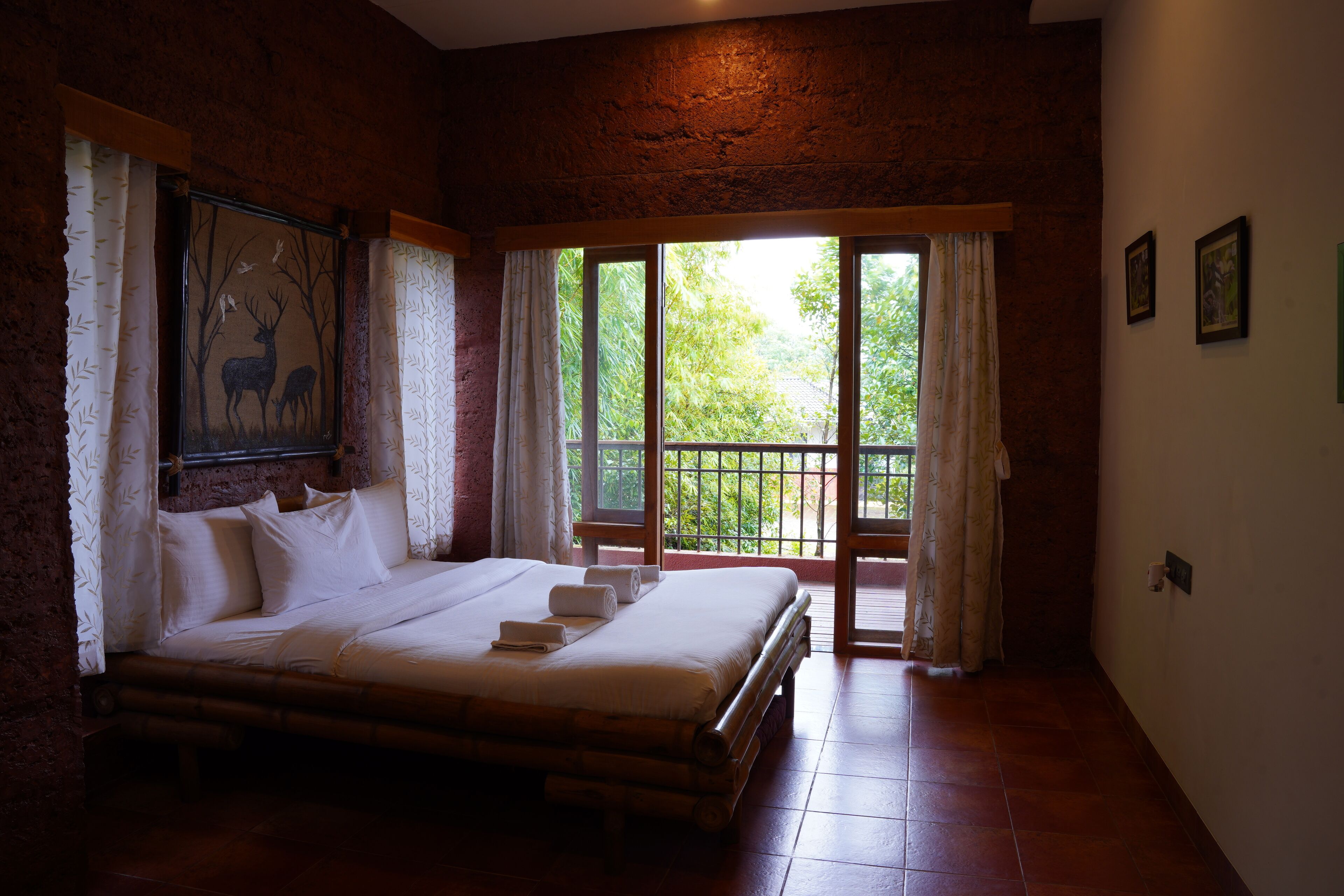 A spacious bedroom with a large bed, a painting of deer, and a balcony with curtains.