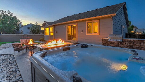 A backyard with a hot tub, outdoor seating, and a fire pit. - TexCo (Colorado Springs)