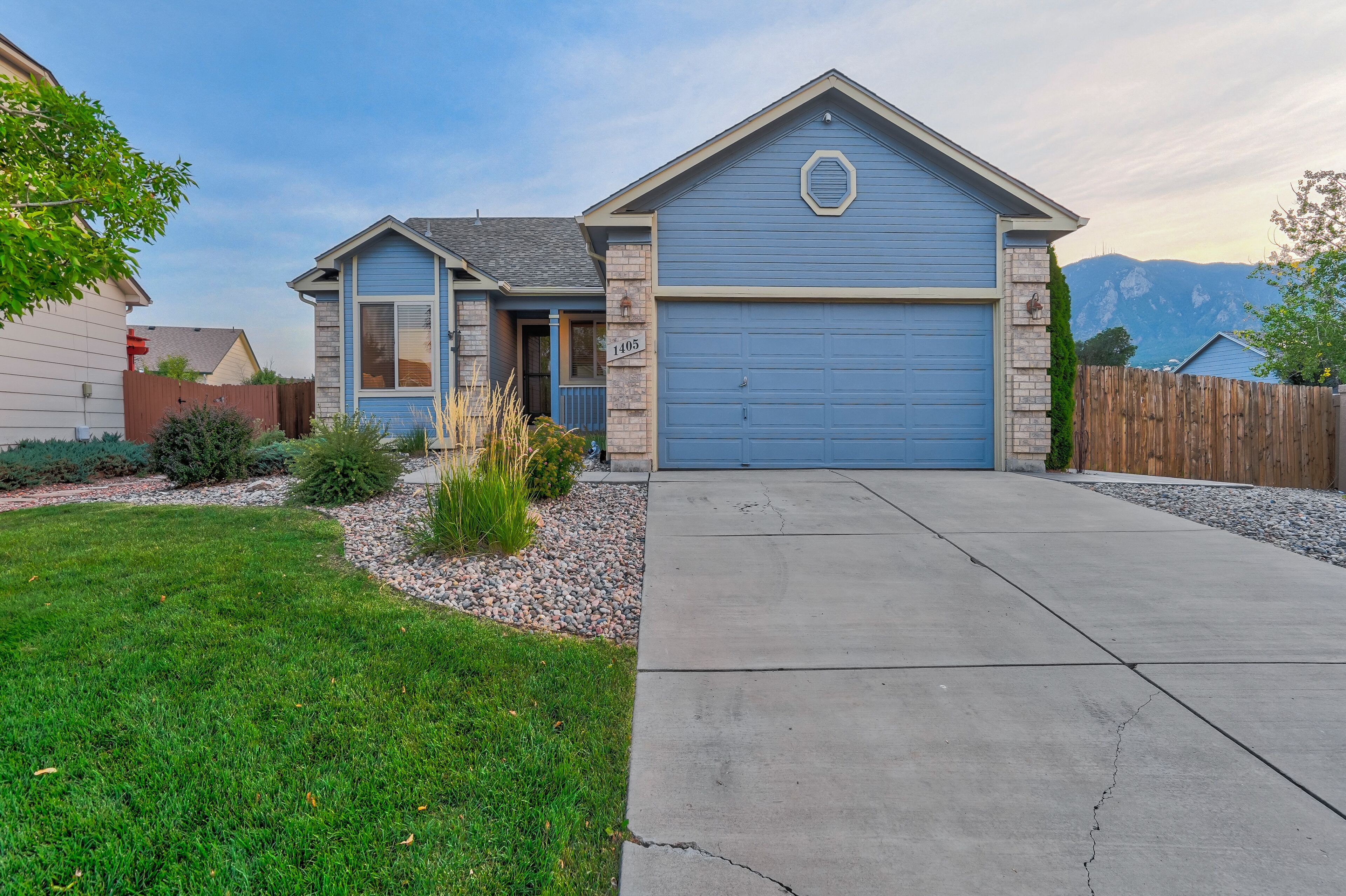 A residential house with a blue garage, a driveway, and a well-maintained lawn.