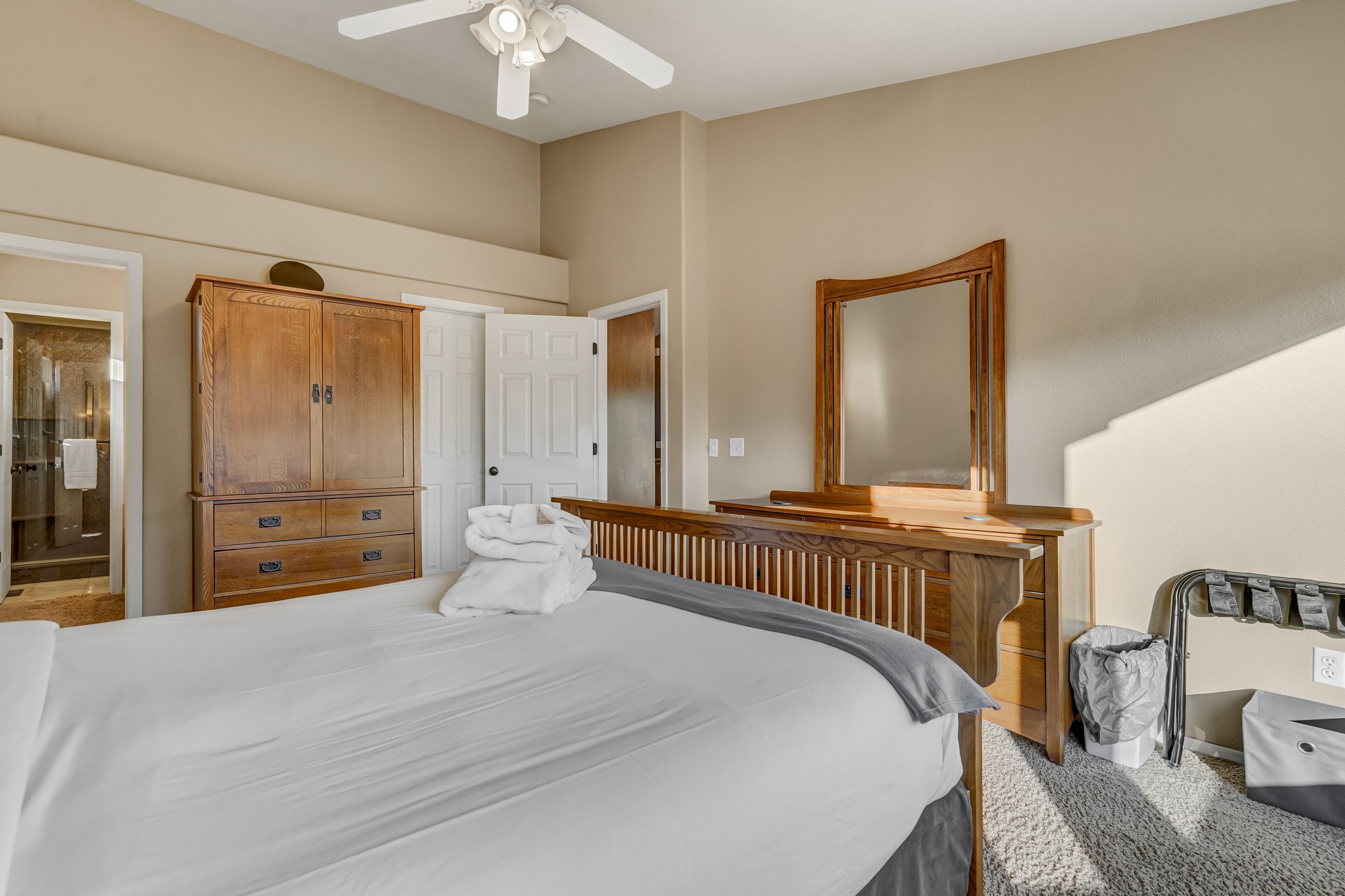 A hotel room with a large bed, wooden wardrobe, and a bathroom with a shower.