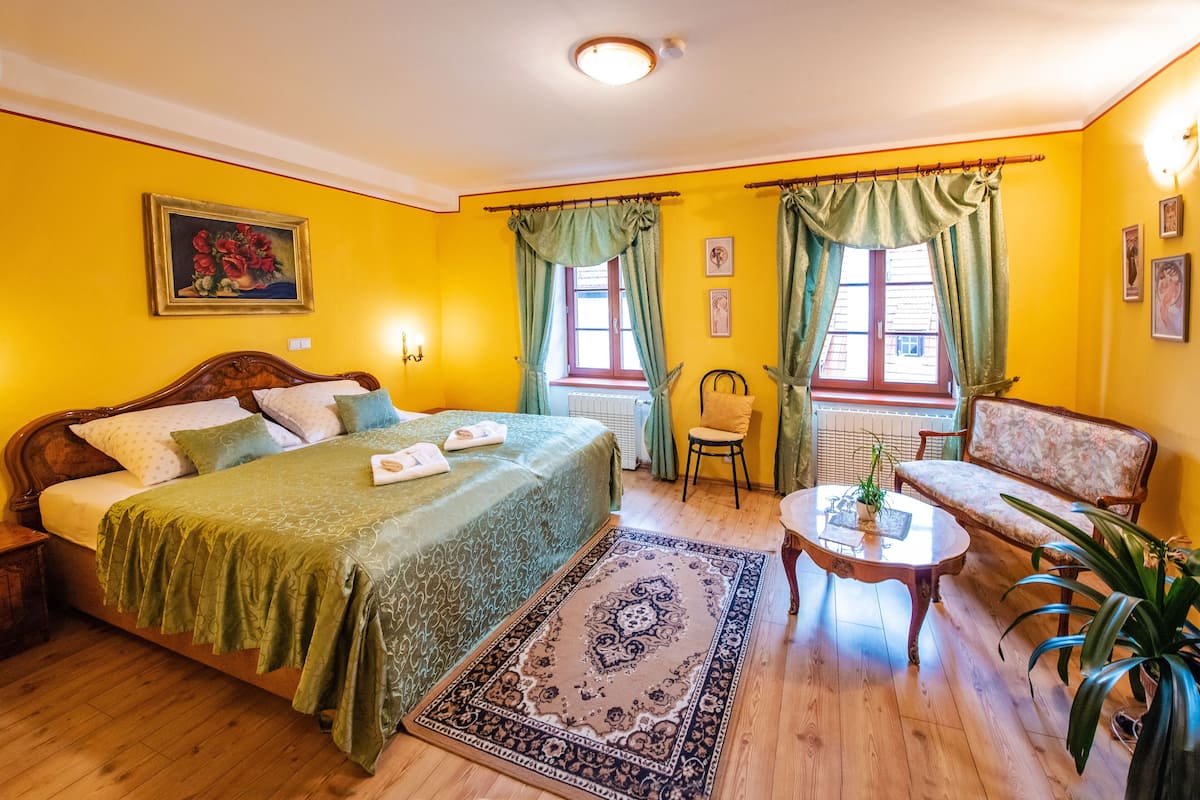 A room with a bed, a chair, a small table, and a window with curtains.