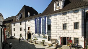 Un edificio histórico con fachada de piedra, grandes lonas azules y una calle adoquinada.