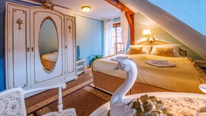 Un dormitorio con cama, cómoda, espejo, estatua de cisne y ventana con cortinas.
