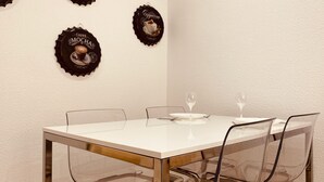 A dining table with four chairs, two wine glasses, and three decorative wall bottle caps.