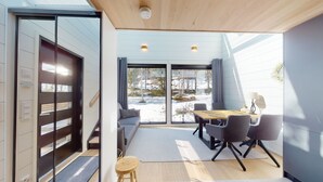A modern interior with a dining area, a staircase, and large windows offering a view of a snowy landscape.