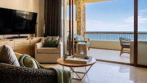 Una sala de estar con una televisión de pantalla plana, un sofá, una mesa de centro y un balcón con vista al mar.