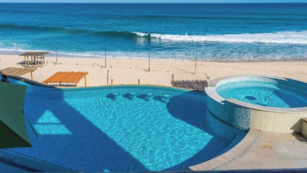 A pool area with clear blue water, a sandy beach, and a view of the ocean. - Soleado 312 Oceanfront Condo at Costa Azul Beach! (San José del Cabo)