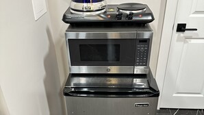 Una cocina compacta equipada con microondas, horno y hervidor.