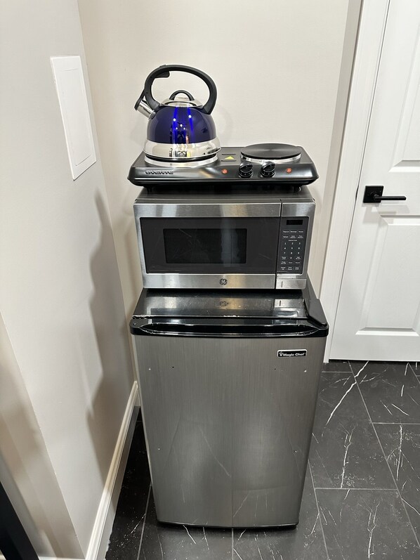 Una cocina compacta equipada con microondas, horno y hervidor.