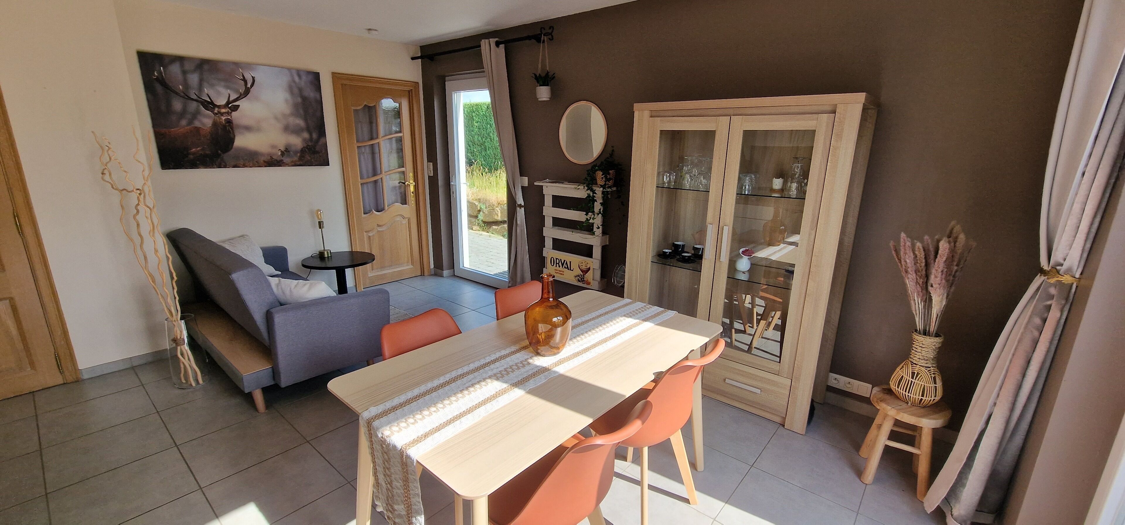 Una sala acogedora con sofá, una mesa de comedor y una vitrina de vidrio.