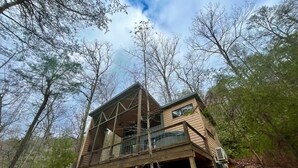 A cabin with a sloped roof, large windows, and a balcony. - Whispering Woods • Modern Cabin w/ HOT TUB (Stanton)