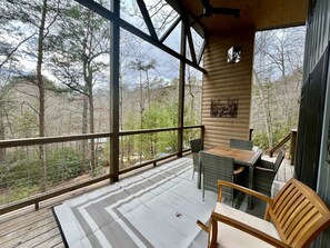 Une terrasse en bois avec une table et des chaises, donnant sur une zone boisée.