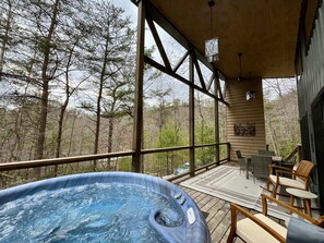 Un bain à remous sur une terrasse en bois, avec vue sur les arbres.