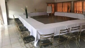 A conference room with a long table and chairs, a whiteboard, and curtains. - Cheltenham Park Resort  (Harare)