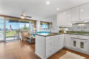 Una cocina moderna con armarios blancos, una isla central y vistas al exterior.