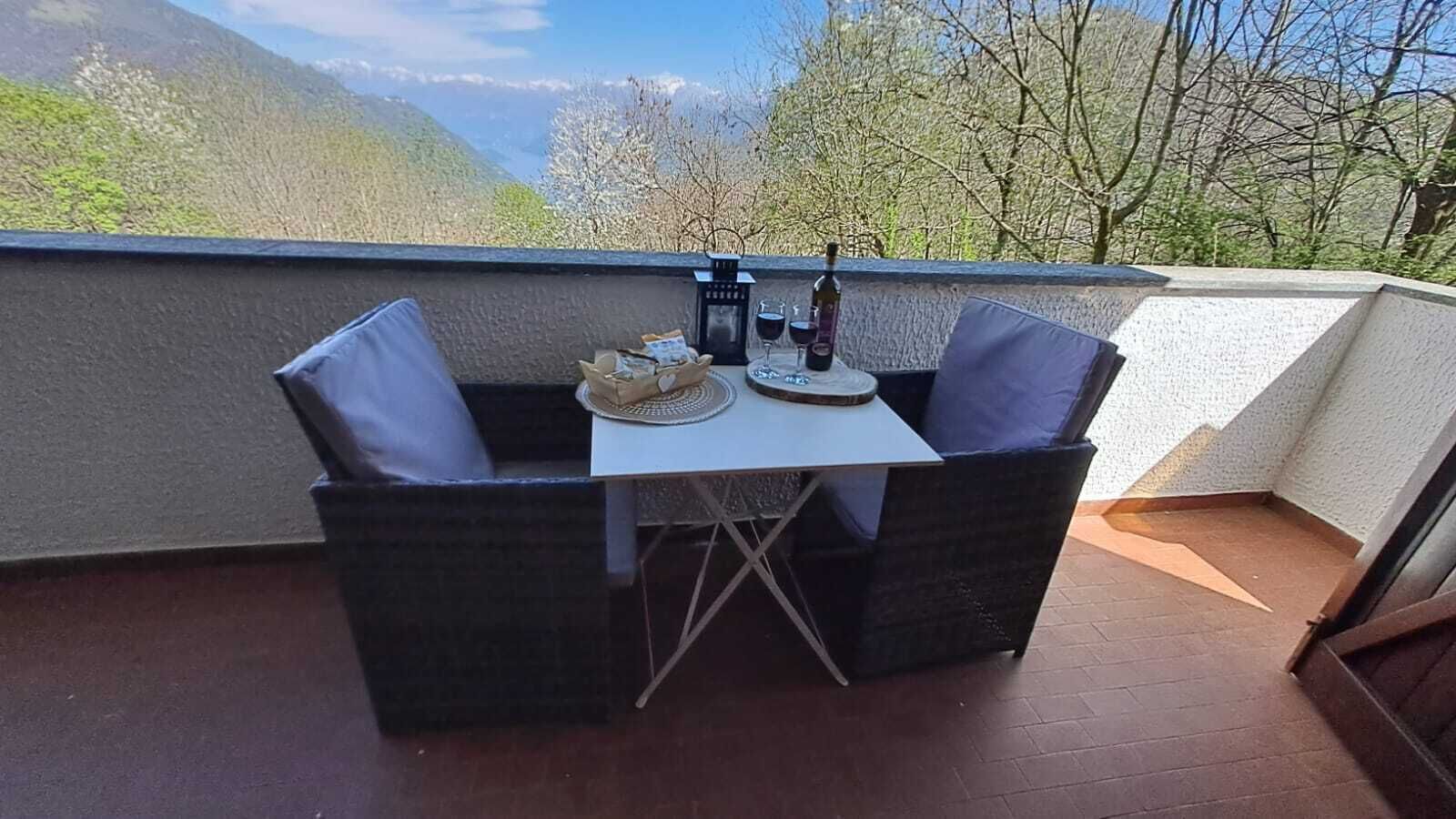 Ein Balkon mit Tisch und Stühlen, einer Weinflasche und Blick auf die Berge.