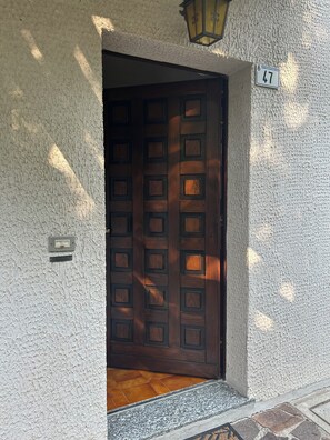 Un mur extérieur à la texture particulière, avec une porte portant le numéro « 47 » et une petite boîte aux lettres.
