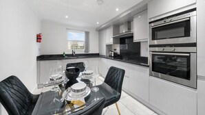 Una cocina moderna con dos hornos, una mesa de comedor con sillas y un ventanal.