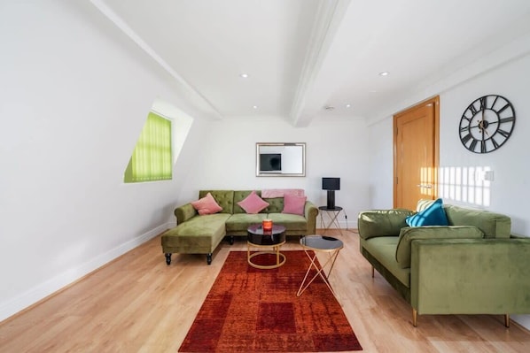 A modern living room with a sectional sofa, a small round table, and a red rug.