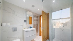 Un baño moderno con inodoro, tocador y zona de ducha.