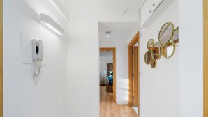 Un pasillo con pared blanca, teléfono y suelo de madera.