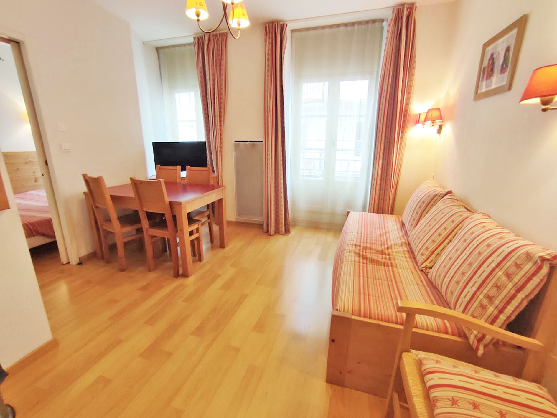 Un espacio habitable compacto con una mesa de comedor de madera, sillas, un sofá y un televisor.