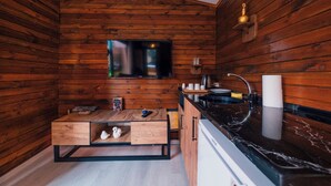 A compact kitchen with wooden walls, a flat-screen TV, a sink, and a small dining area. - Kurtköy Park Bungalov Evleri (Sapanca)