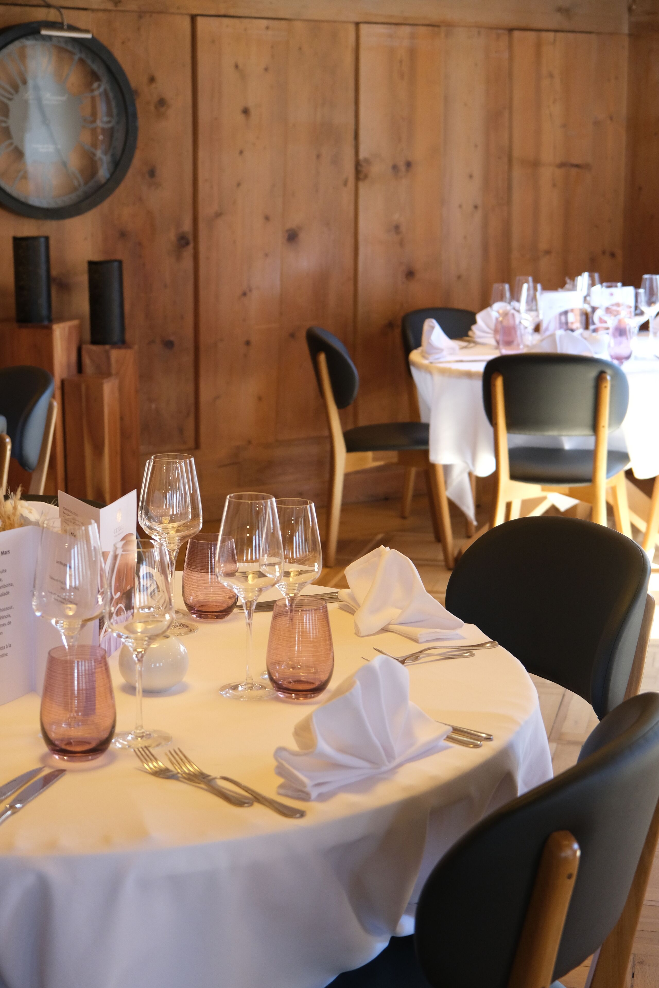 Uma mesa de jantar posta com taças de vinho, talheres e um cardápio.