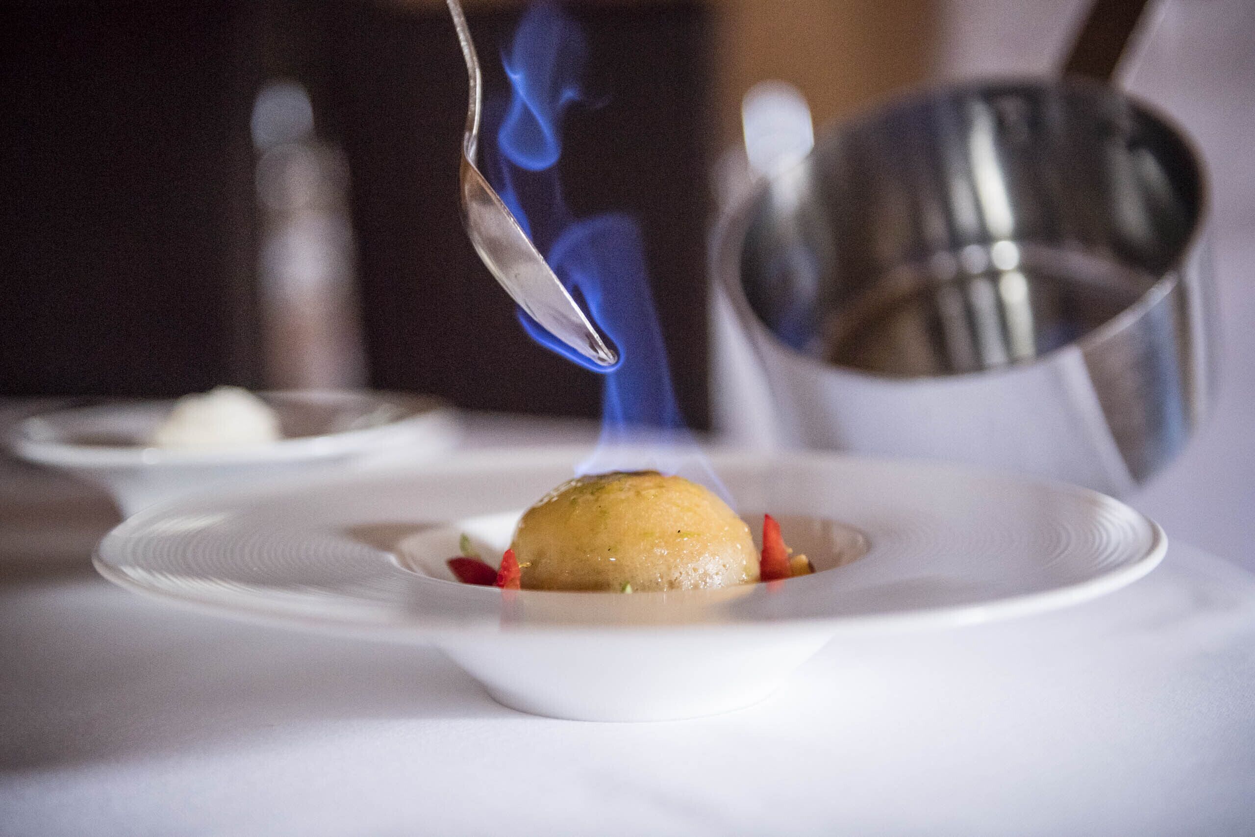 Ein Dessert mit einem Löffel blauem Feuer auf einem weißen Teller.