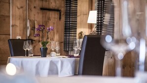 A dining table set with wine glasses, a vase with purple flowers, and a lamp.