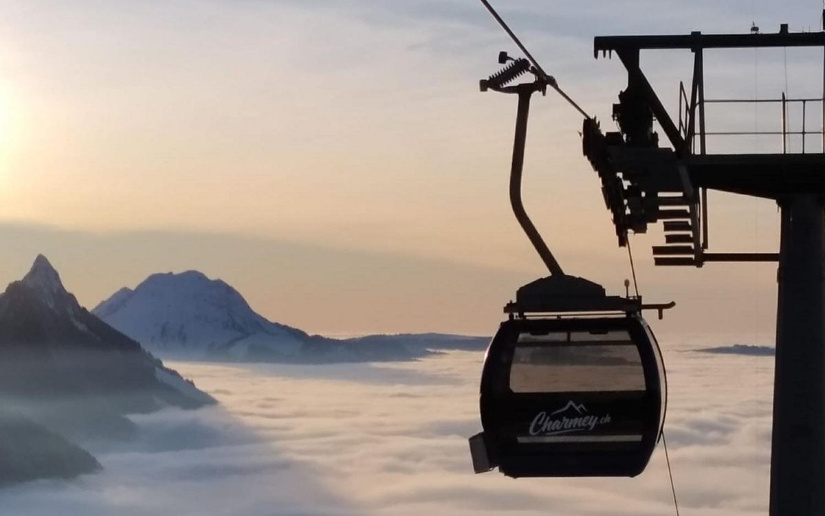 Un telesilla con vistas a una cordillera y nubes abajo.