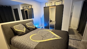 Een slaapkamer met een bed, een kast, een spiegel en een deur.