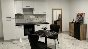 Een moderne keuken met witte kasten, een marmeren aanrechtblad en zwarte stoelen.