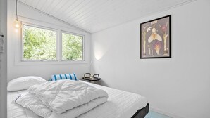 A bedroom with a bed, a bedside table, a chair, and a window with a view of trees. - Awesome home in Højby with WiFi (Højby)