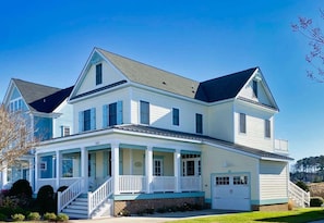 A two-story house with a front porch, a garage, and a well-maintained lawn. - Sunny Side Up - Chesapeake Properties (Cape Charles)