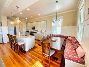 A spacious kitchen with white cabinets, a central island, and a dining area with a bench.