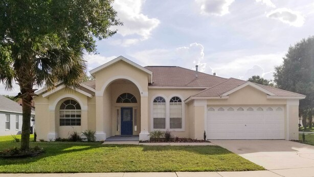 A single-story house with a beige exterior, a blue front door, and a garage. - Cozy Nook Villa w/ Pool: 10 Mi to Park Entrance! (Clermont)