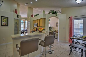 A kitchen with a bar area, wooden cabinets, and a microwave.