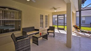 A covered patio with wicker furniture, ceiling fans, and large windows offering views of the outdoors. - Cozy Nook Villa w/ Pool: 10 Mi to Park Entrance! (Clermont)