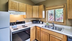A compact kitchen with wooden cabinets, a stove, a microwave, and a sink. - Trego Cabin w/ Mtn Views, Easy Access to Lake (Trego)