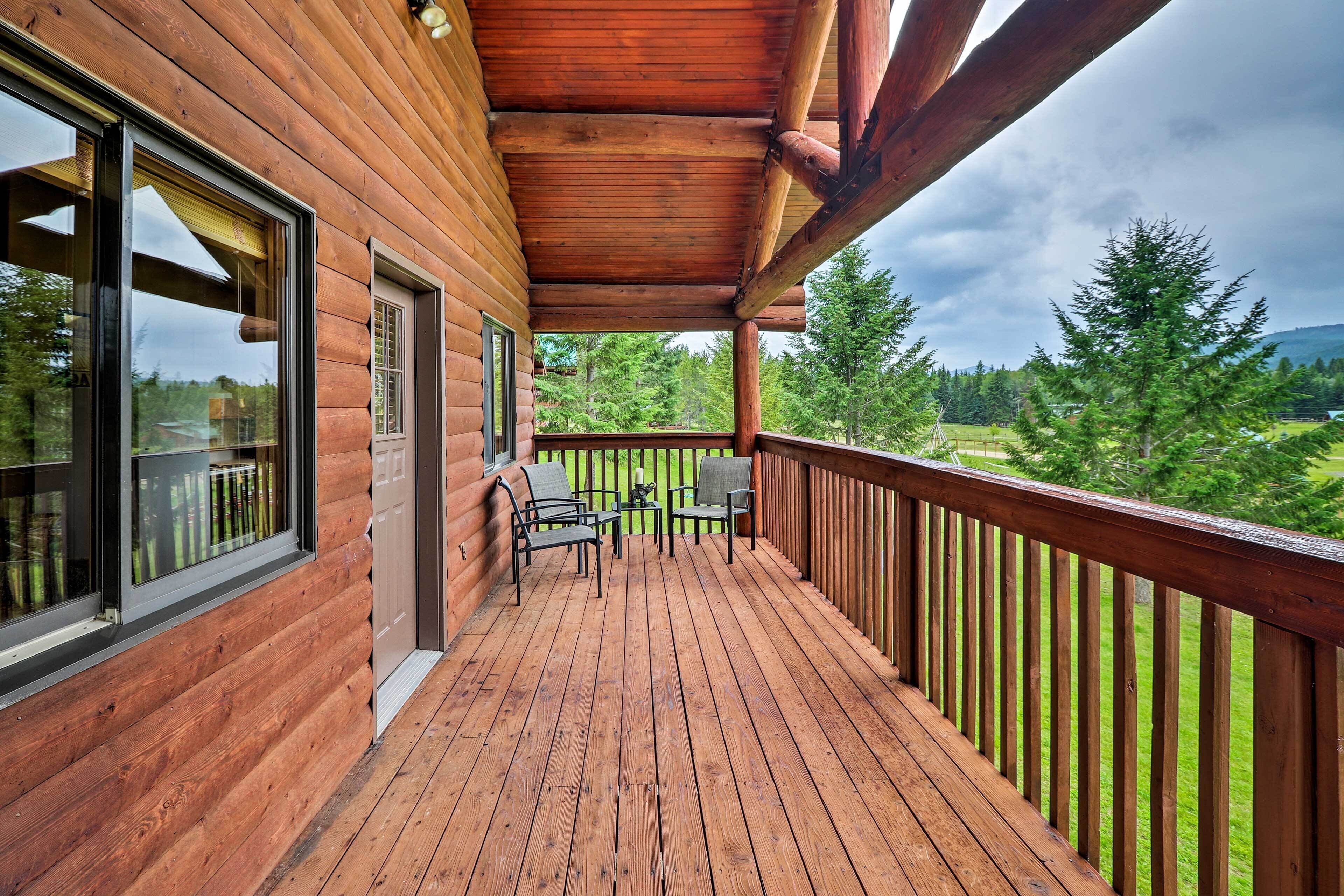 A wooden deck with a view of a forest and mountains.