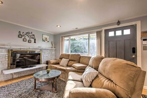 A living room with a sectional sofa, a fireplace, a flat-screen TV, and a large window. - Seattle Area Getaway ~ 5 Mi to Puget Sound! (Mountlake Terrace)