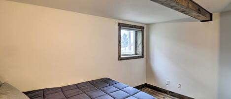 Une chambre à coucher avec un lit, une fenêtre et un plafond avec des poutres en bois.