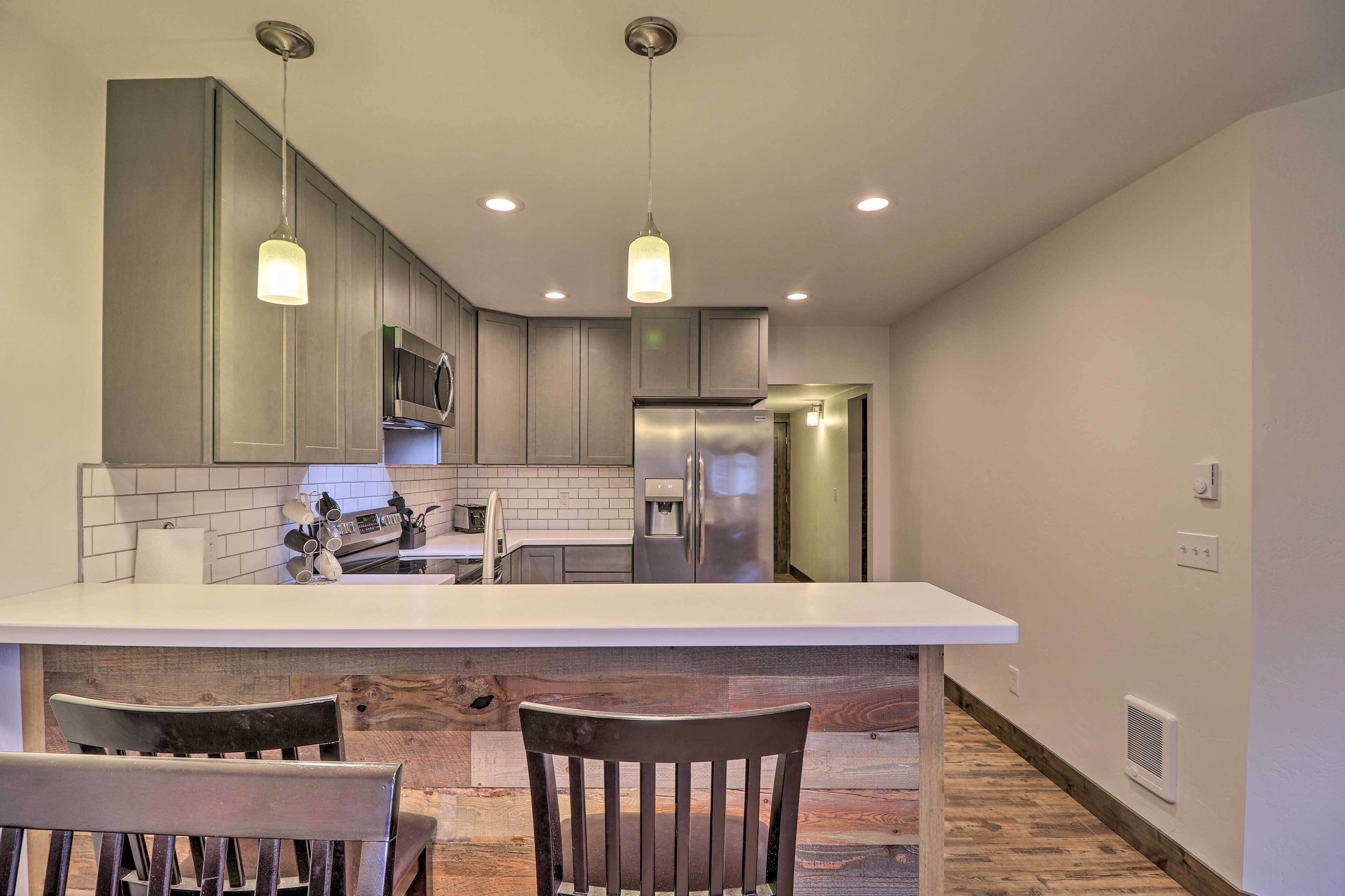 A modern kitchen with a central island, stainless steel appliances, and pendant lighting.