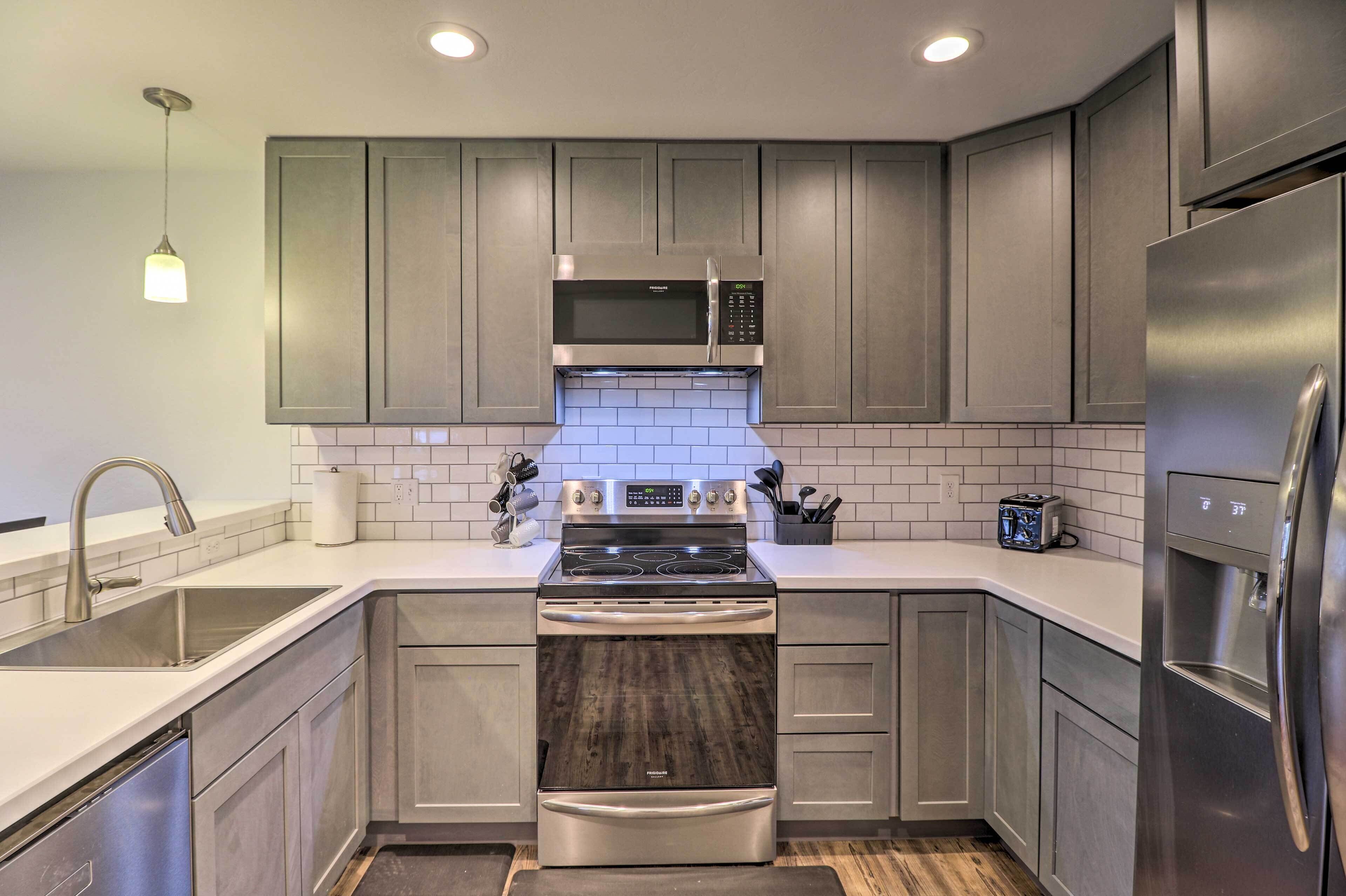 Una cocina moderna con gabinetes grises, electrodomésticos de acero inoxidable y salpicadero de azulejos.